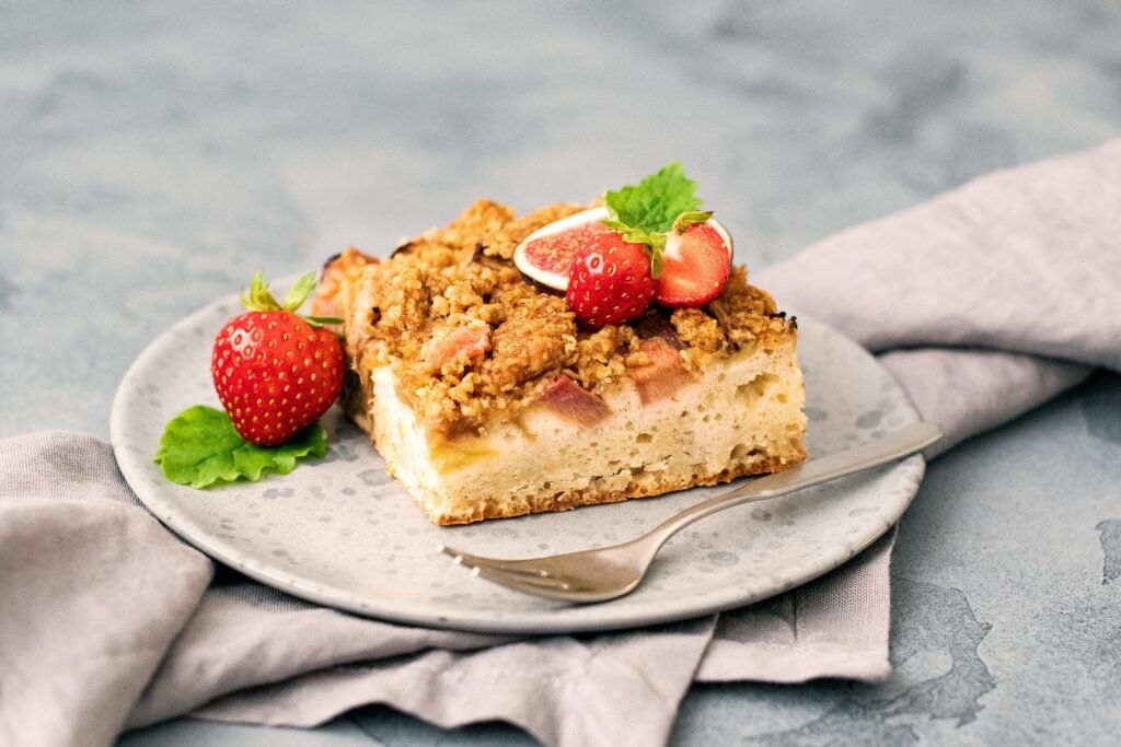 A slice of homemade cake topped with fresh strawberries and mint, perfect for a healthy dessert.