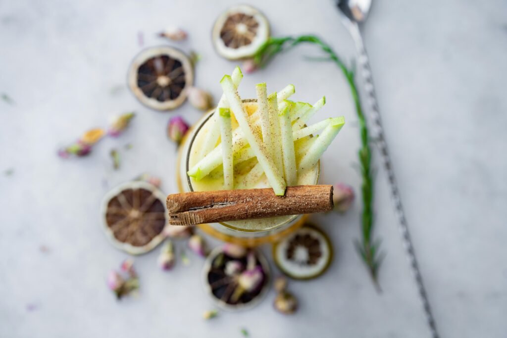 Elegant apple cinnamon cocktail garnished with dried citrus and flowers, perfect for a refreshing summer drink.