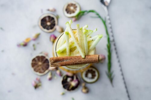 Elegant apple cinnamon cocktail garnished with dried citrus and flowers, perfect for a refreshing summer drink.