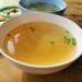 Delicious homemade soup garnished with scallions in a bowl on a rustic wooden table.