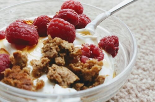 Close-up of a breakfast bowl with yogurt, fresh raspberries, and granola.