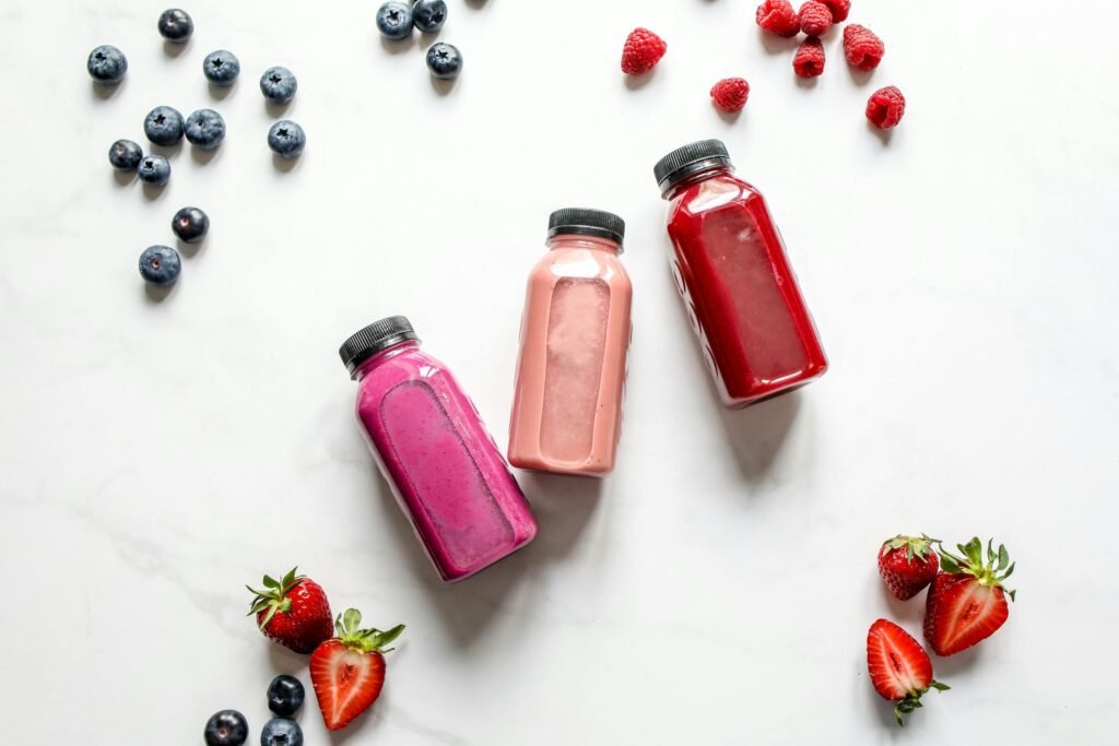 Vibrant array of fruit smoothies with fresh raspberries, strawberries, and blueberries.