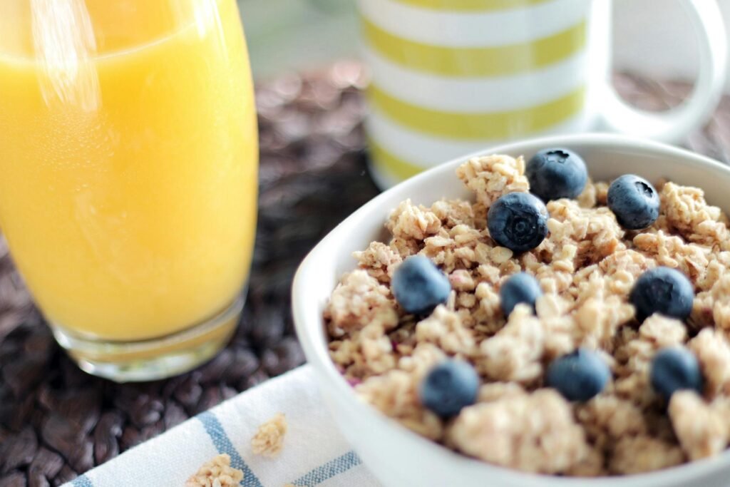 Delicious breakfast bowl with muesli, blueberries, and fresh orange juice, perfect for a healthy start.
