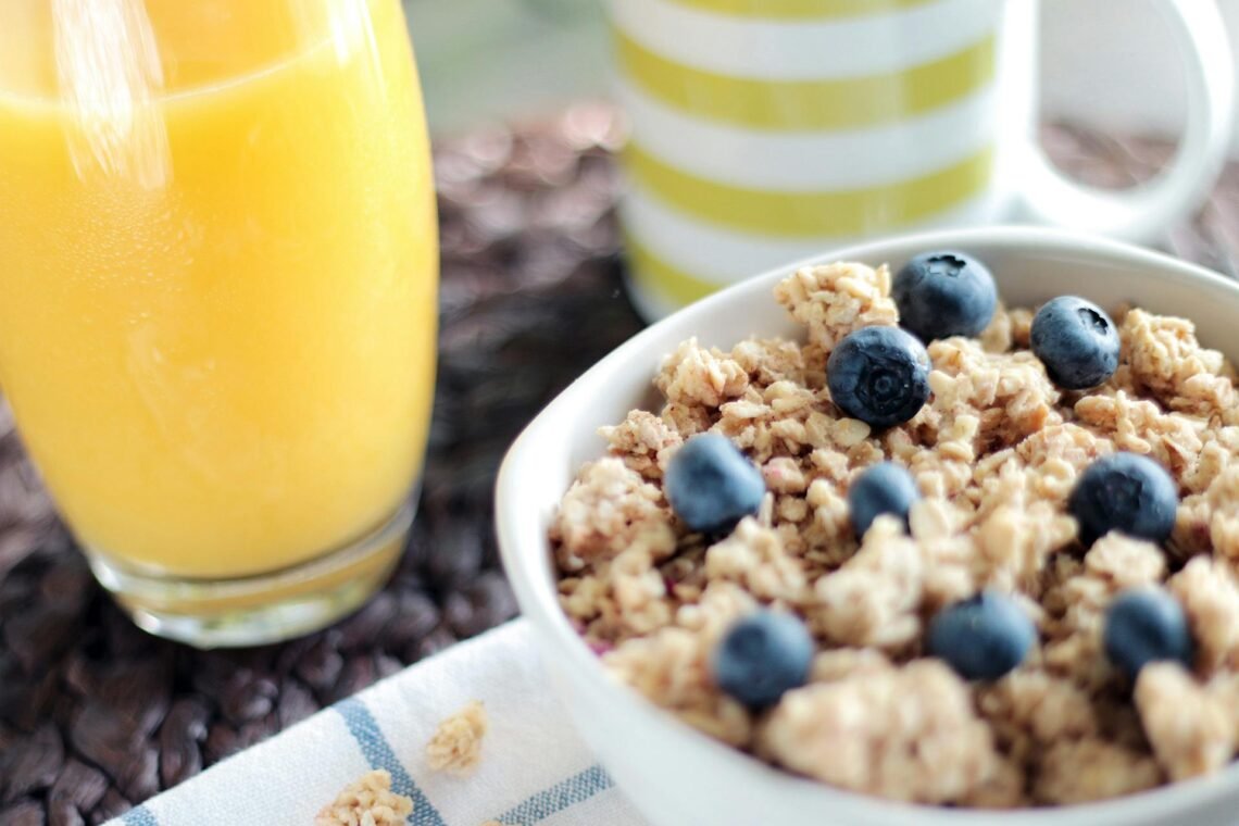 Delicious breakfast bowl with muesli, blueberries, and fresh orange juice, perfect for a healthy start.