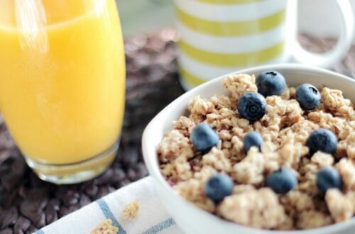 Delicious breakfast bowl with muesli, blueberries, and fresh orange juice, perfect for a healthy start.