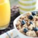 Delicious breakfast bowl with muesli, blueberries, and fresh orange juice, perfect for a healthy start.