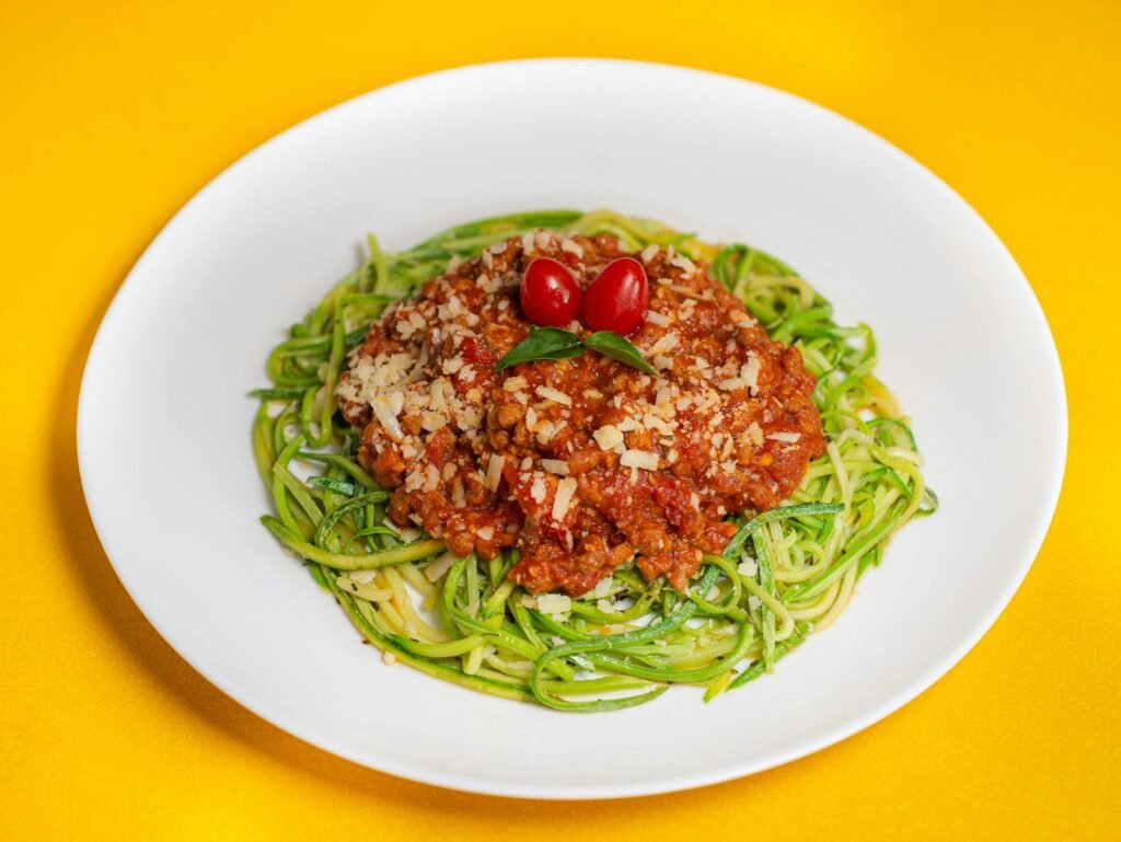 A vibrant dish featuring zucchini noodles topped with savory Bolognese and cherry tomatoes.