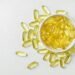 High-angle shot of omega-3 fish oil capsules in a ceramic bowl on a white background.