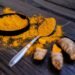 Vibrant turmeric powder and root on a dark wooden surface, emphasizing natural spices.