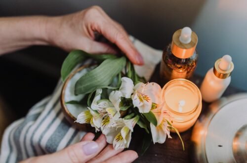 Ambient candlelit setting with hands arranging delicate white flowers, evoking tranquility.