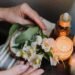 Ambient candlelit setting with hands arranging delicate white flowers, evoking tranquility.