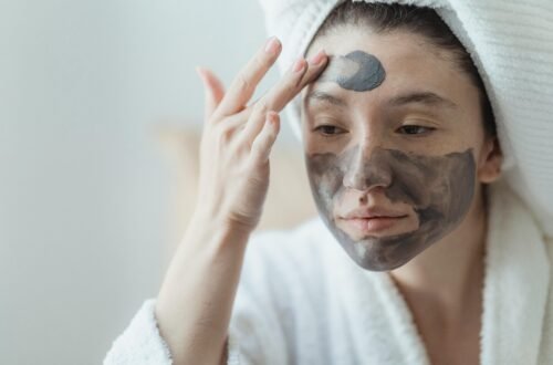 Adult woman relaxing with a clay face mask, enhancing skin health and wellness indoors.