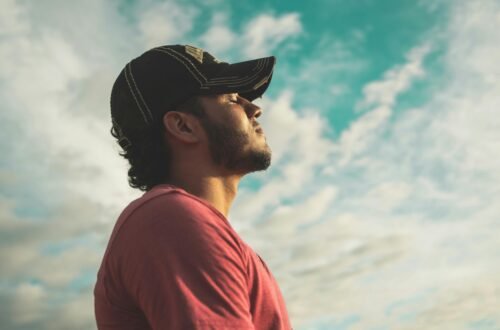 A man enjoys outdoor relaxation and mindfulness beneath a bright, cloudy sky, exuding calm and peace.