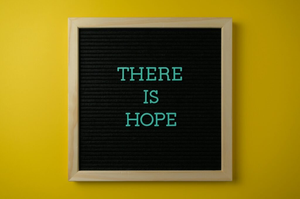 Letter board with 'THERE IS HOPE' message against a vibrant yellow backdrop.