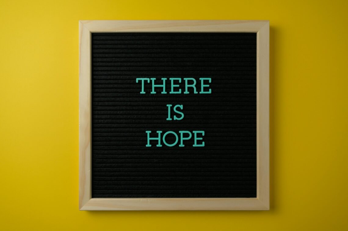 Letter board with 'THERE IS HOPE' message against a vibrant yellow backdrop.
