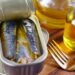 Close-up of canned sardines in olive oil with a fork on a wooden surface.